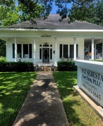 Pat Sebesta Law Firm - A white home with a sign in front of it.